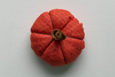 orange circle of fabric on white table, during construction process to turn it into a pumpkin; completed image