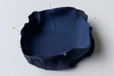 round pincushion construction step on white table with fabric and pins