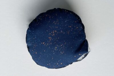 round pincushion construction step on white table with fabric and pins