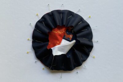 round pincushion construction step on white table with fabric and pins