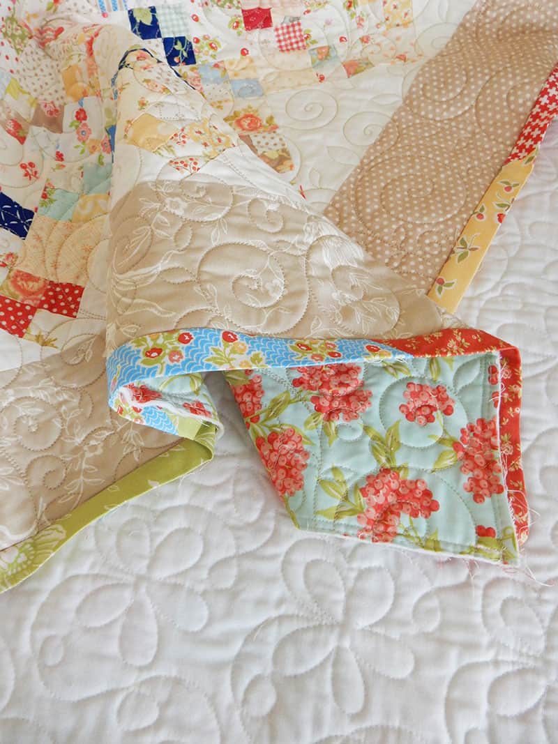 scrappy binding sewn onto a quilt waiting to be hand sewn