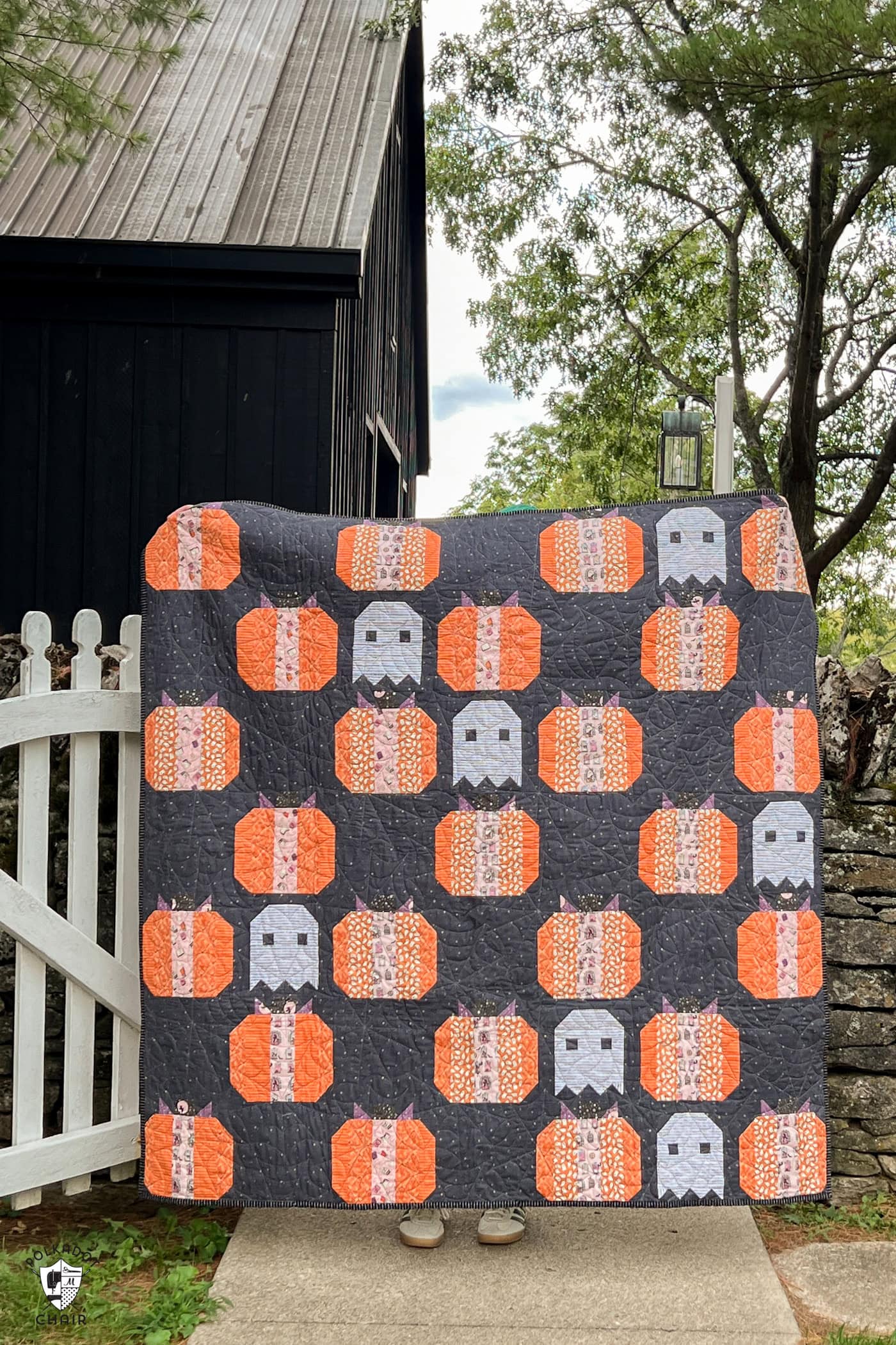 gray quilt outdoors, pumpkin quilt with dark gray background and white ghosts quilt blocks
