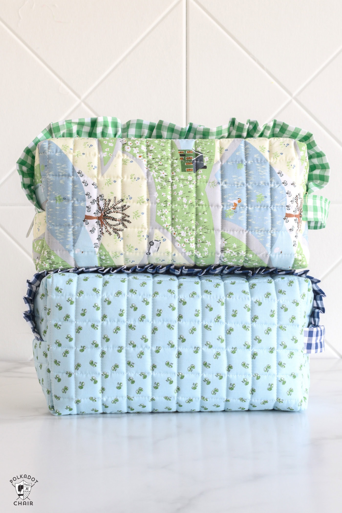 close up of two blue and green ruffle zip pouches on white table