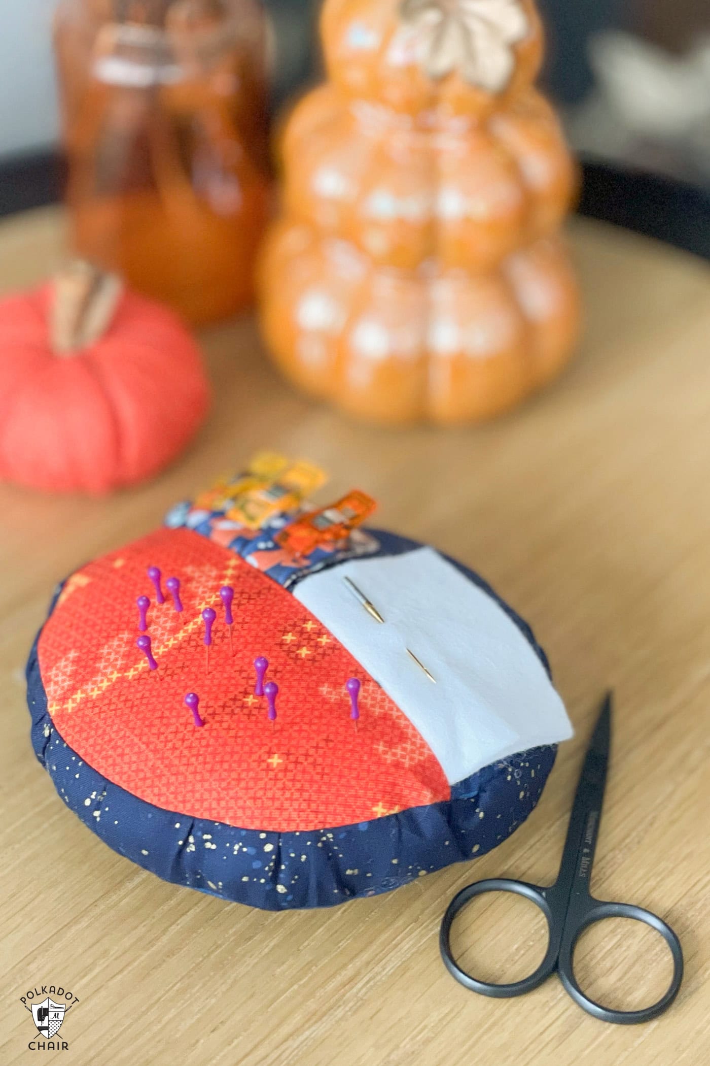 orange and blue round pincushion on wood table