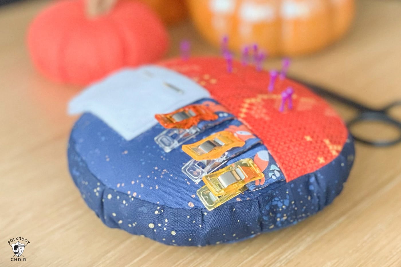 orange and blue round pincushion on wood table