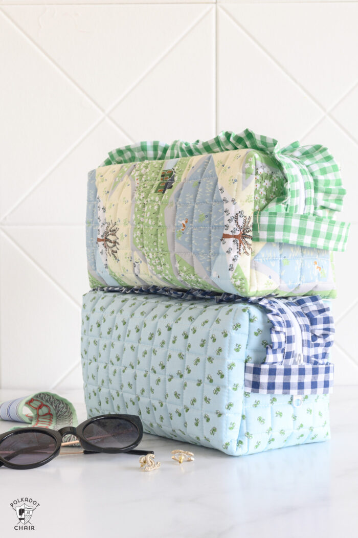 close up of two blue and green ruffle zip pouches on white table