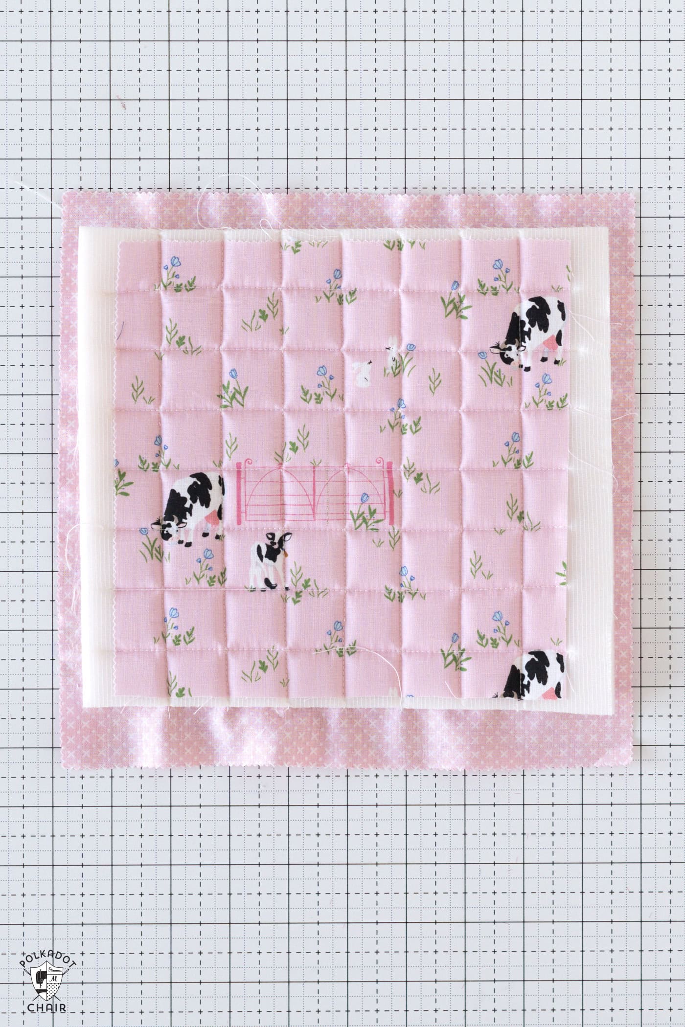 pink square of fabric quilted on white cutting mat