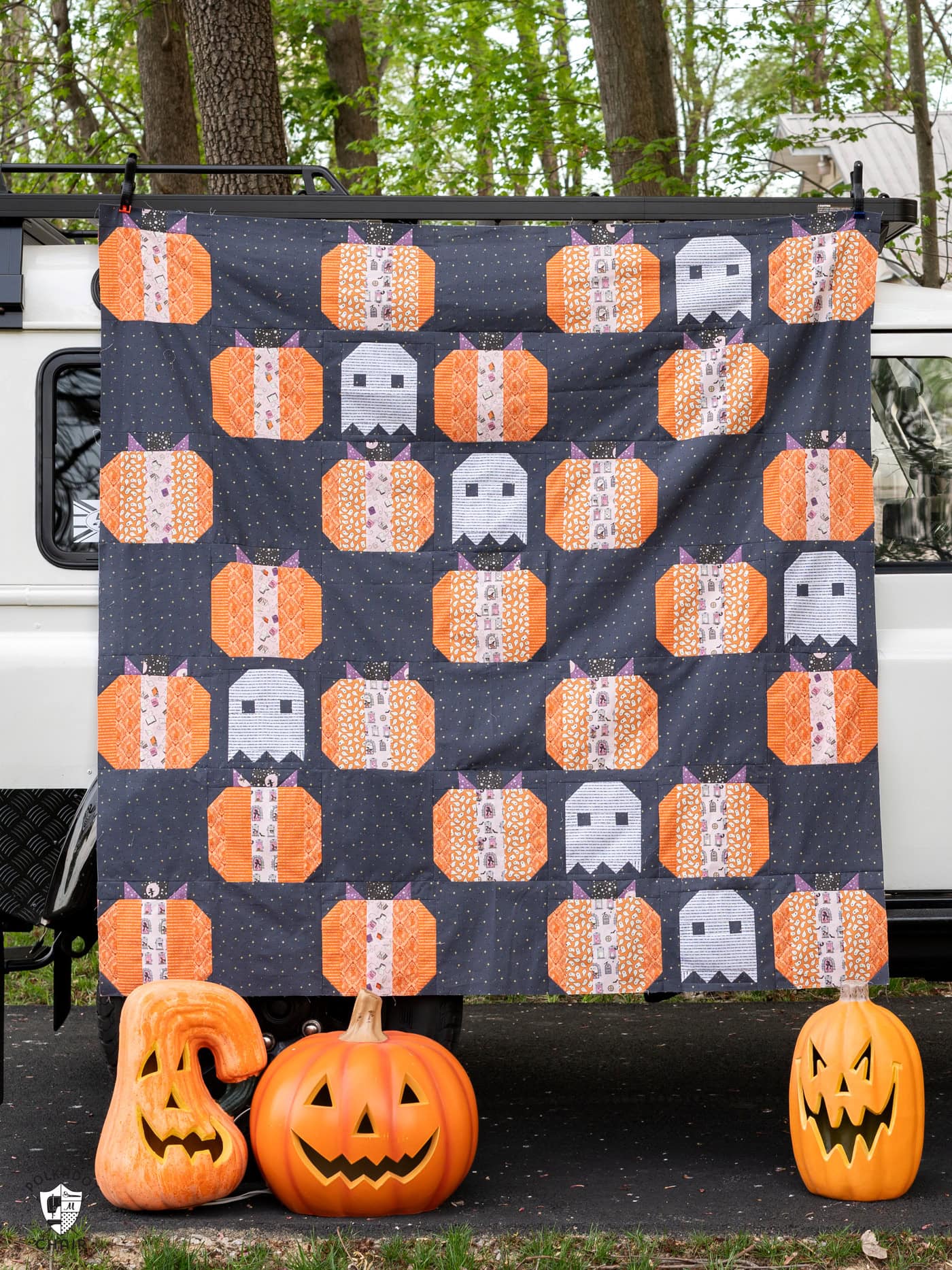 gray quilt outdoors, pumpkin quilt with dark gray background and white ghosts quilt blocks