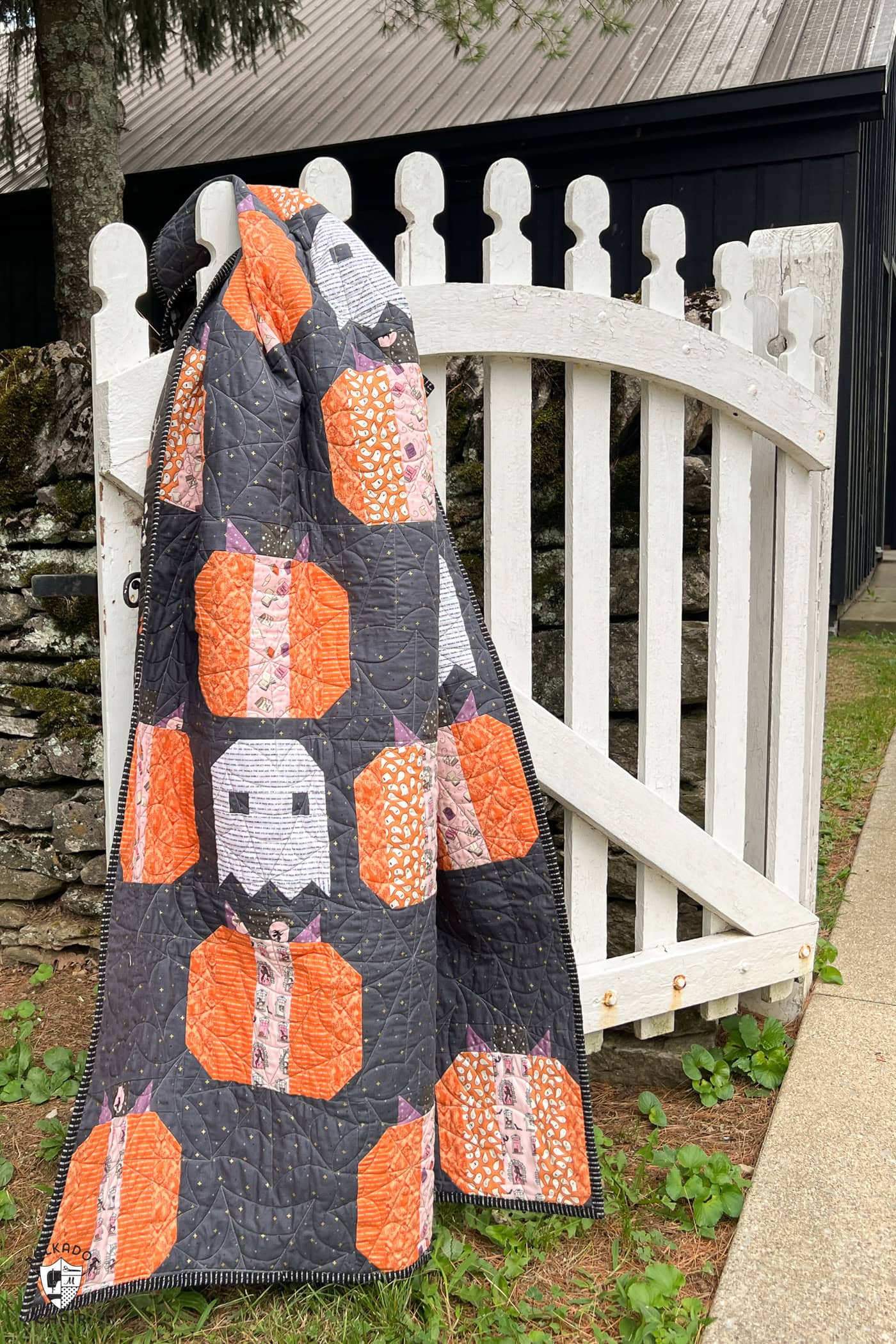 gray quilt outdoors, pumpkin quilt with dark gray background and white ghosts quilt blocks