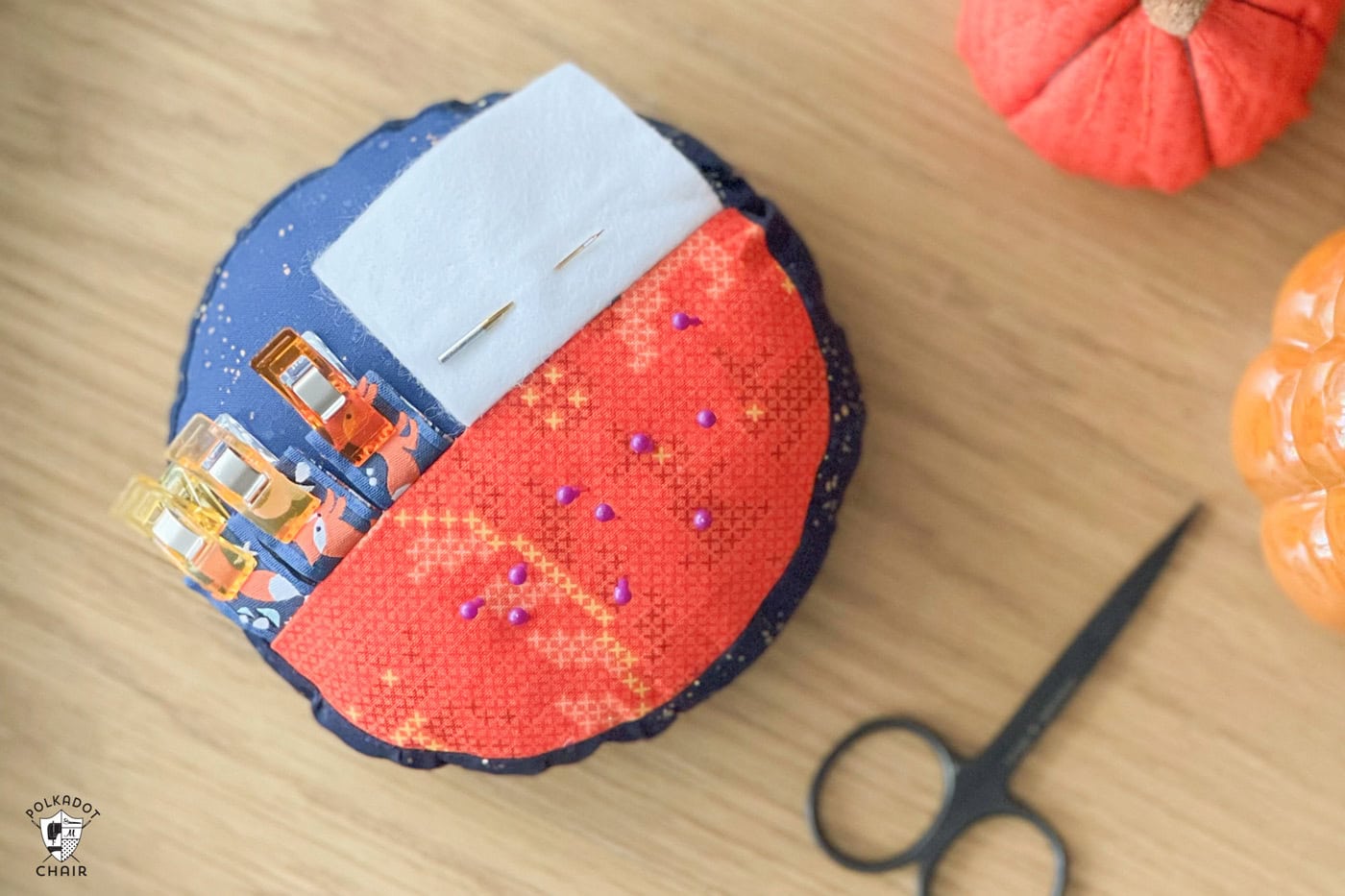 orange and blue round pincushion on wood table