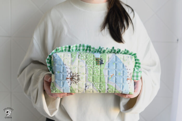 close up of two blue and green ruffle zip pouches on white table