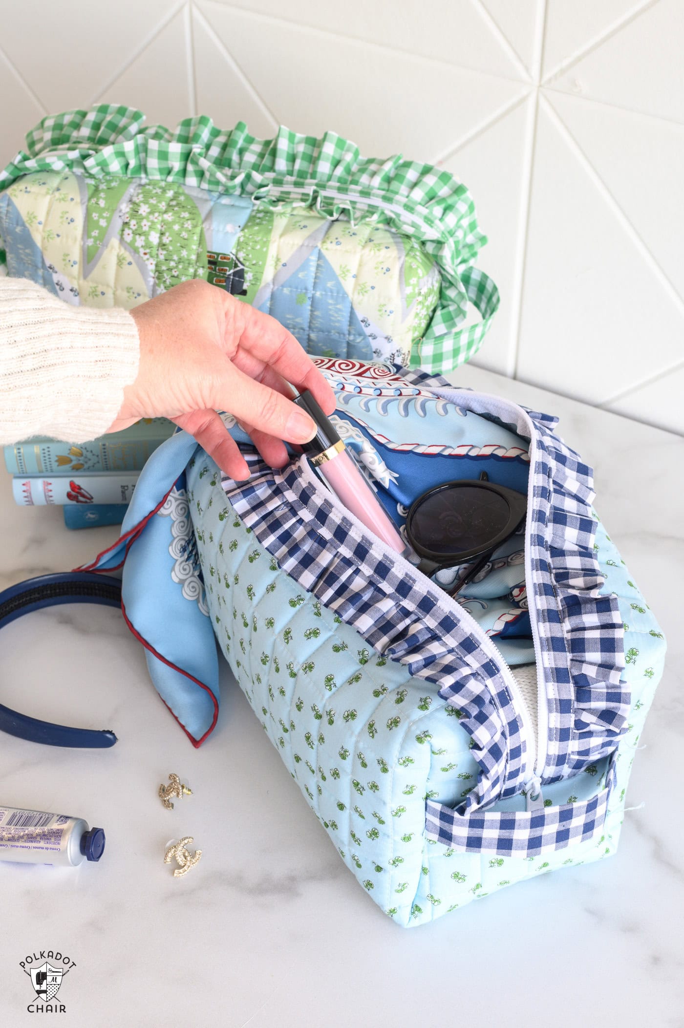 image of two ruffle zip pouches with scarf, and lip gloss on white table