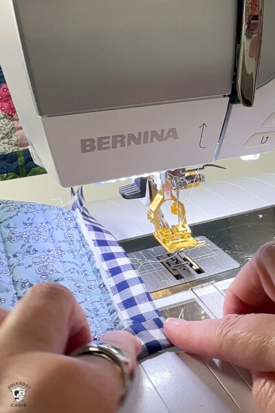hand sewing blue fabric under sewing machine foot