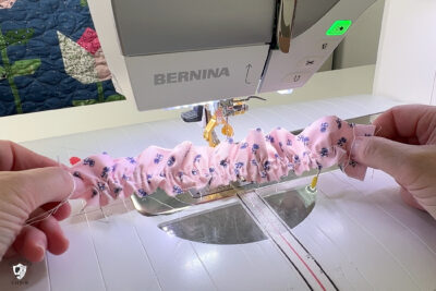 hand sewing pink fabric under sewing machine foot