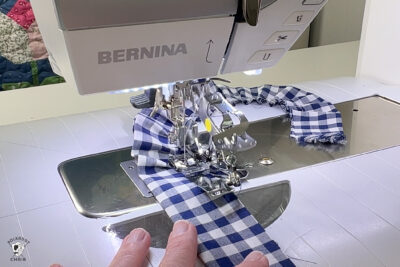 hand sewing blue fabric under sewing machine foot
