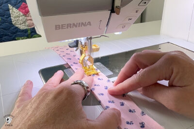 hand sewing pink fabric under sewing machine foot