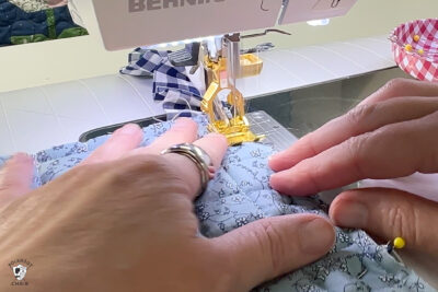 hand sewing blue fabric under sewing machine foot