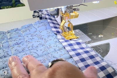 hand sewing blue fabric under sewing machine foot