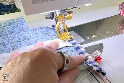 hand sewing blue fabric under sewing machine foot