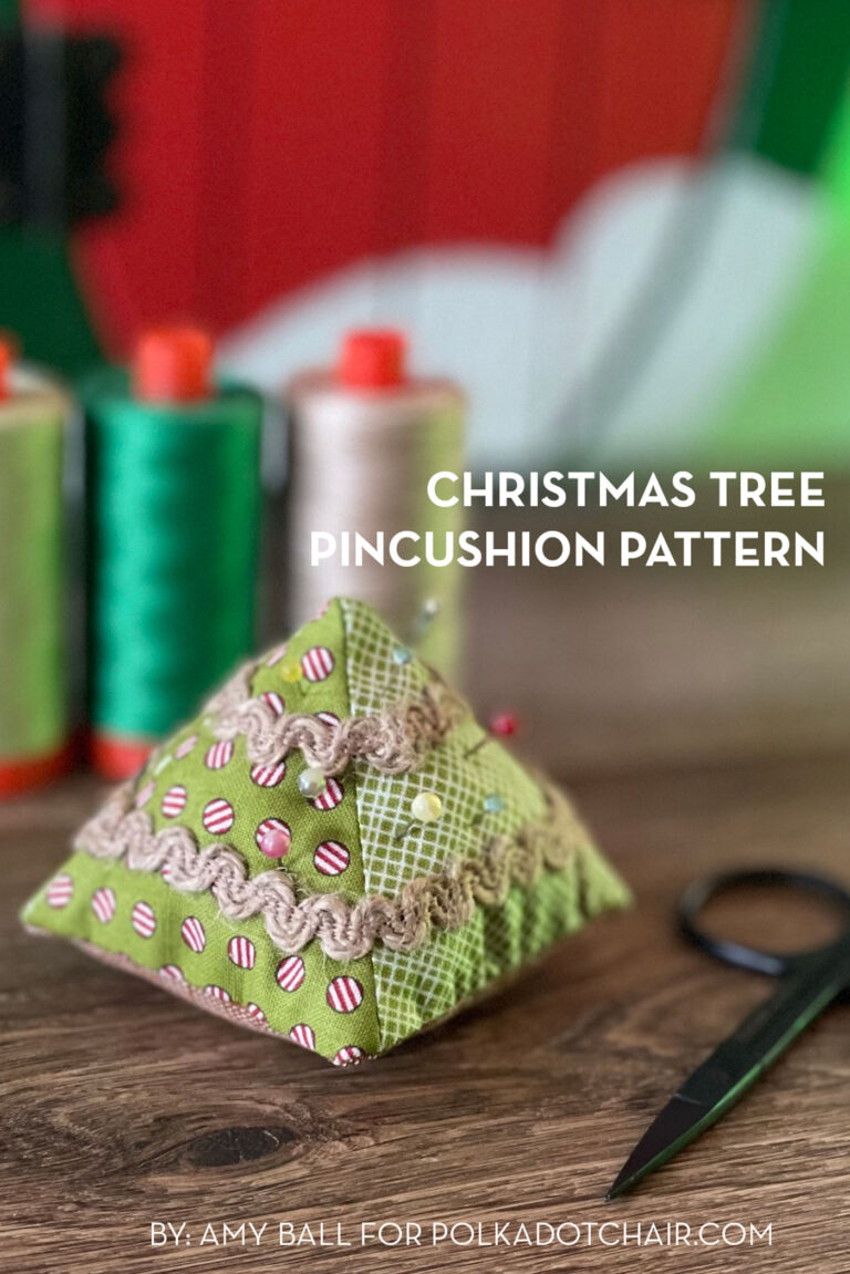 Christmas tree pincushion on wood table with thread in the background
