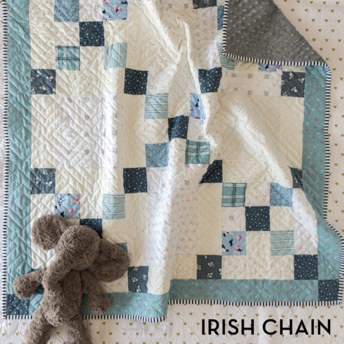 blue and ivory baby quilt on bed with gray elephant toy