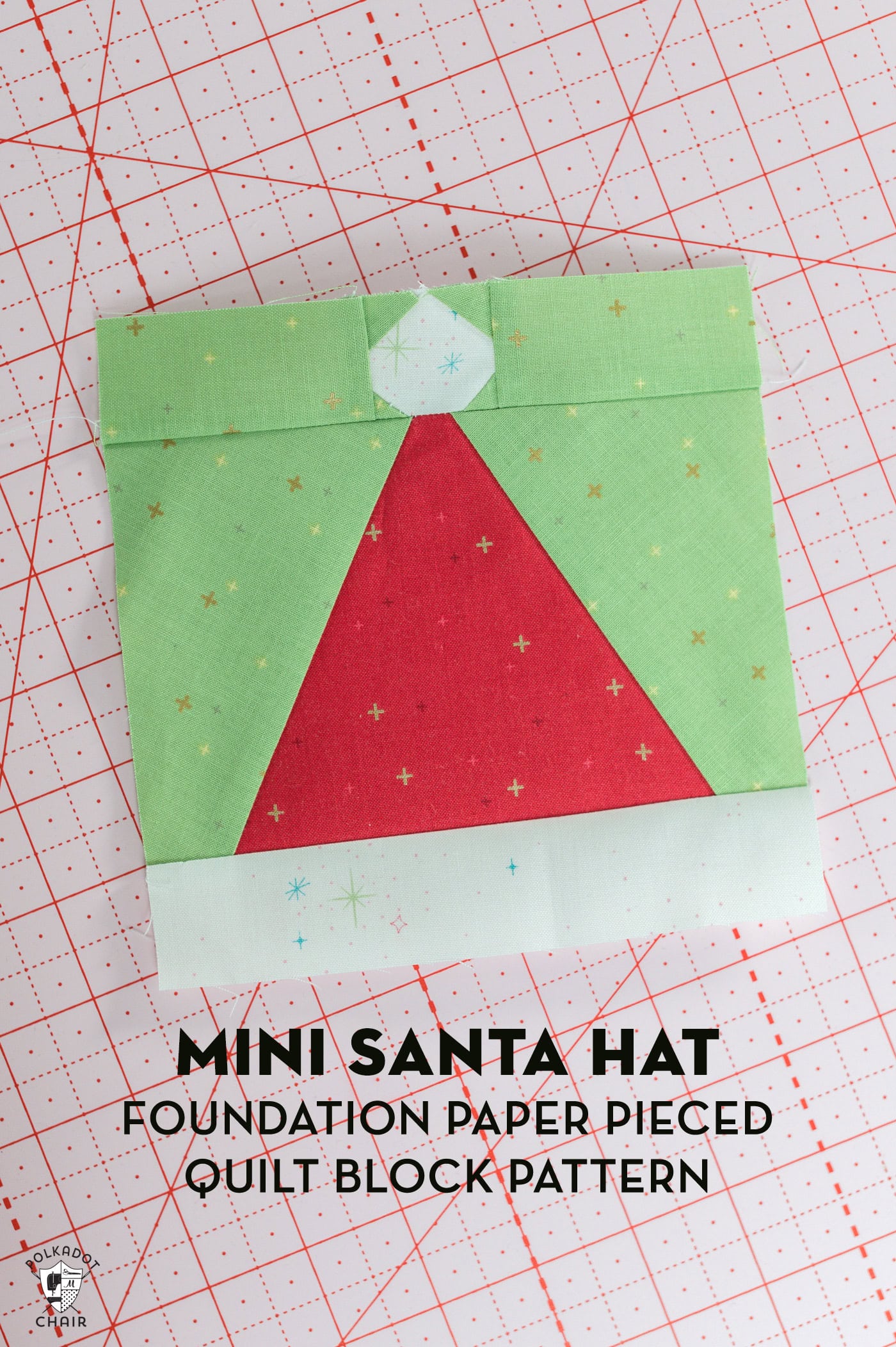 red and white pieced santa claus hat quilt block with green background on pink cutting mat