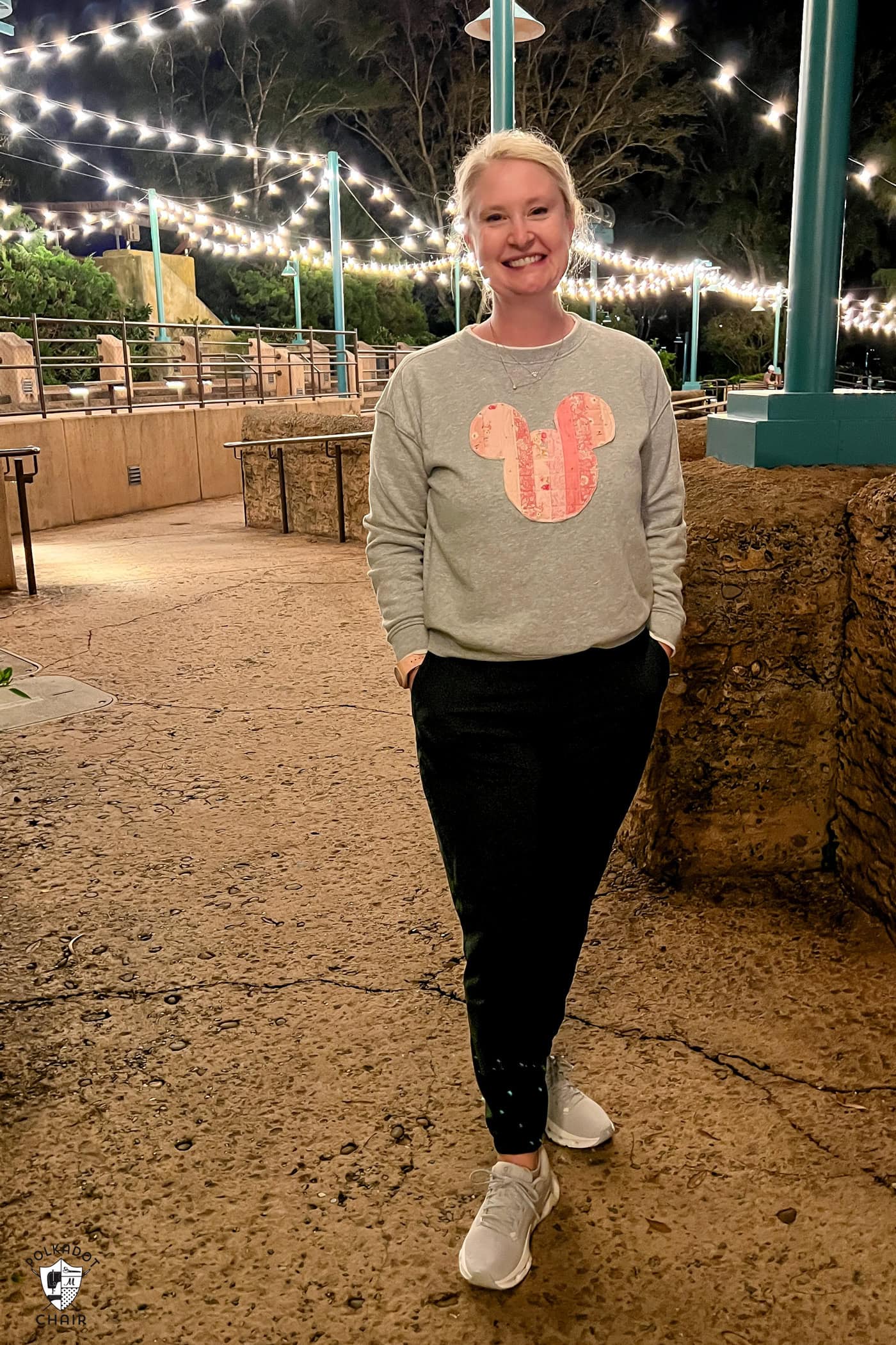 woman in gray sweashirt standing outside at night under lights