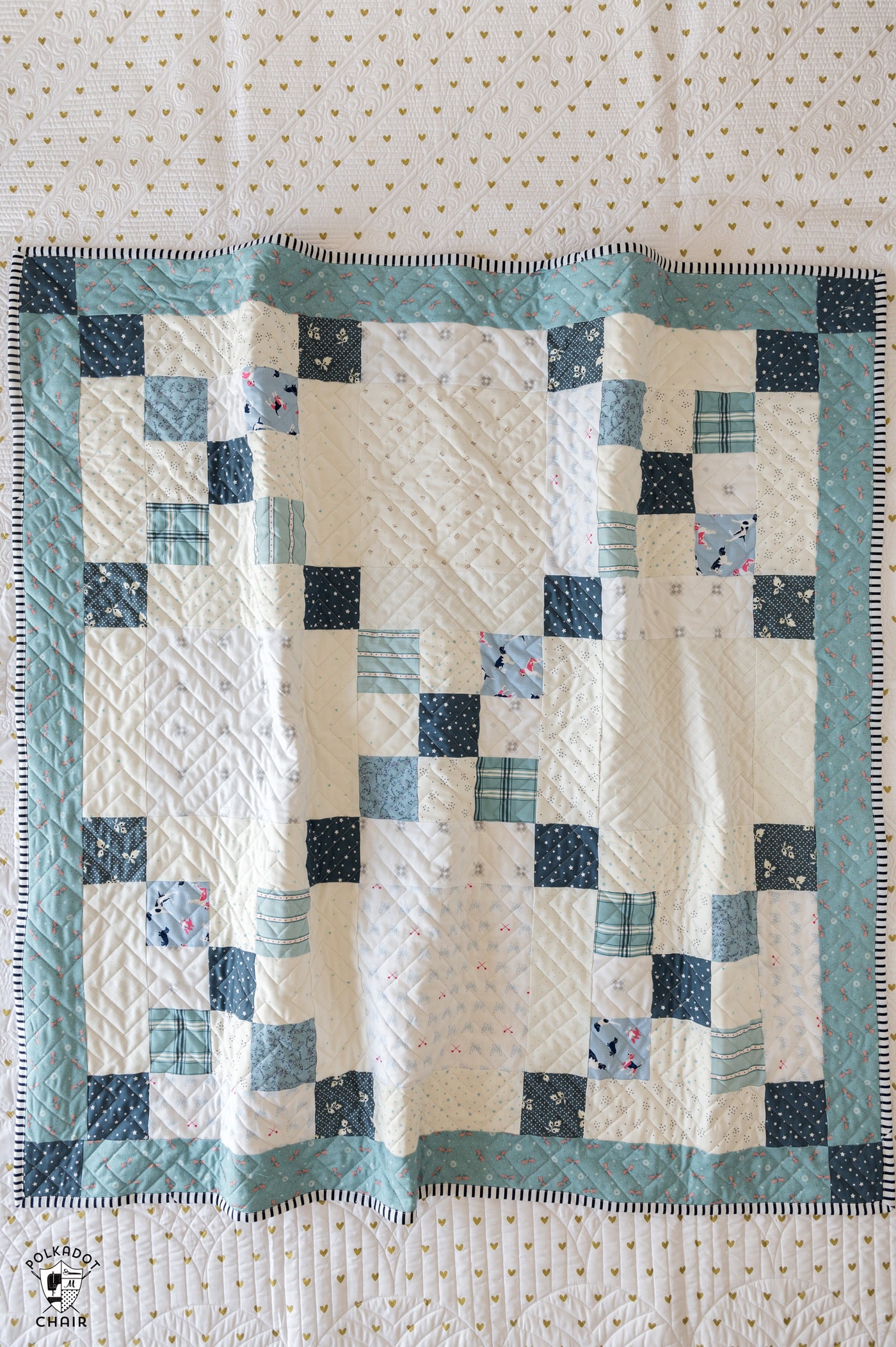 blue and ivory baby quilt on bed