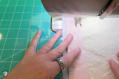 pink fabric under sewing machine foot being sewn