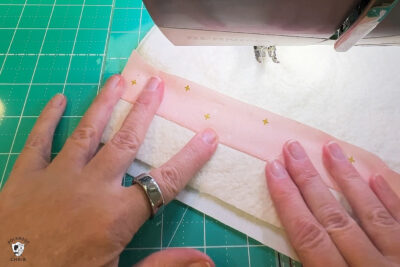 pink fabric under sewing machine foot being sewn
