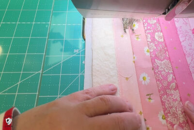 pink fabric under sewing machine foot being sewn