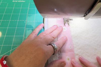 pink fabric under sewing machine foot being sewn