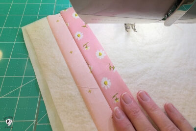 pink fabric under sewing machine foot being sewn