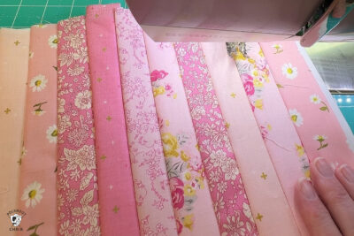 pink fabric under sewing machine foot being sewn