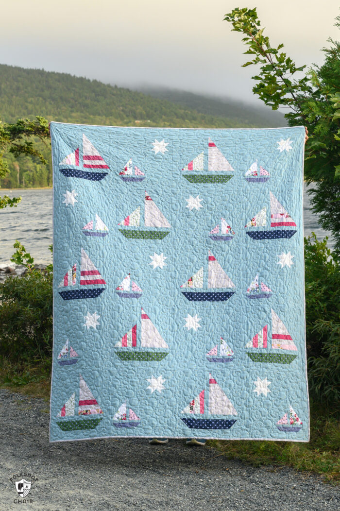 Blue quilt with white, red and green sailboat quilt blocks outdoors