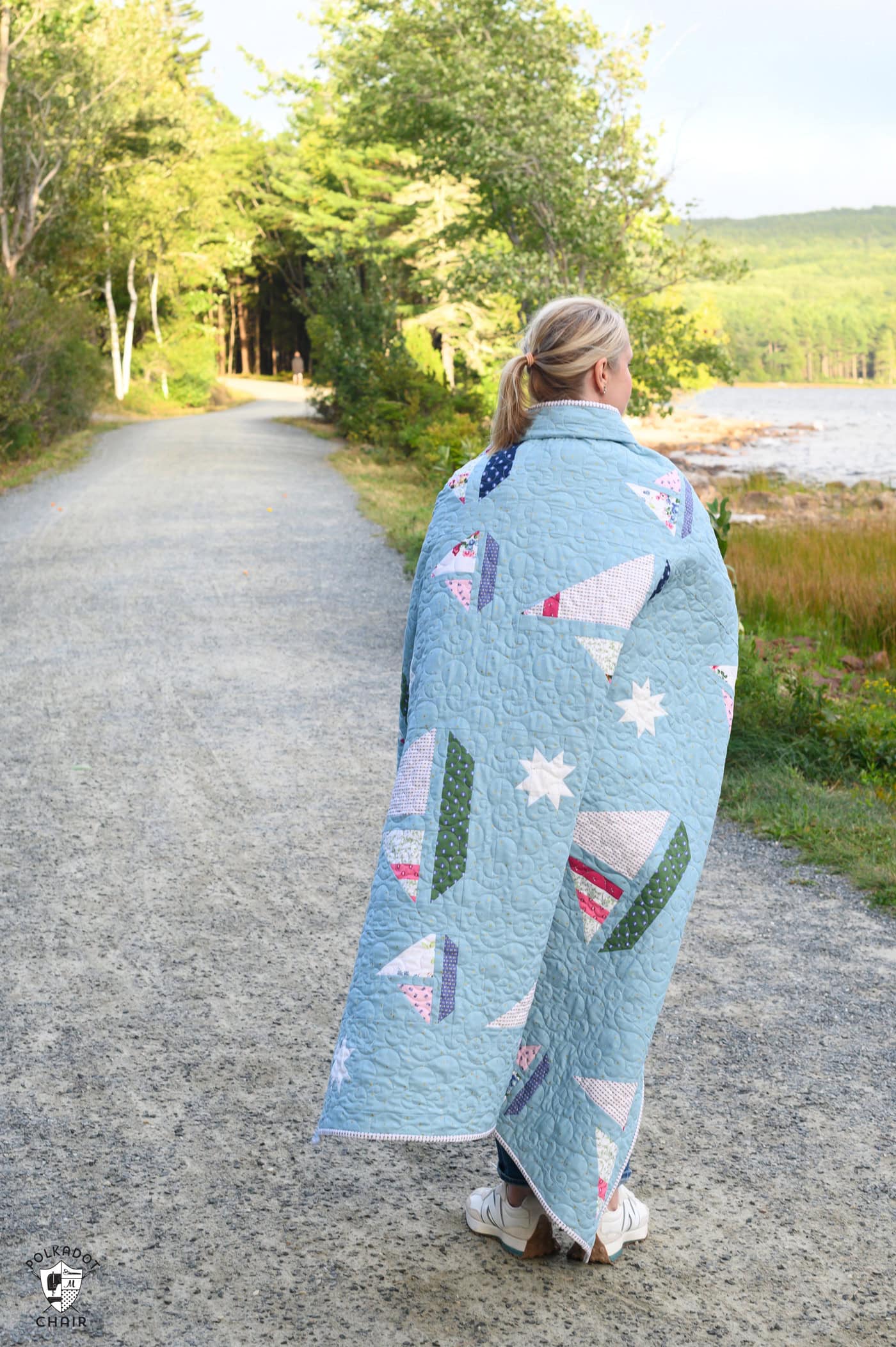 Blue quilt with white, red and green sailboat quilt blocks outdoors