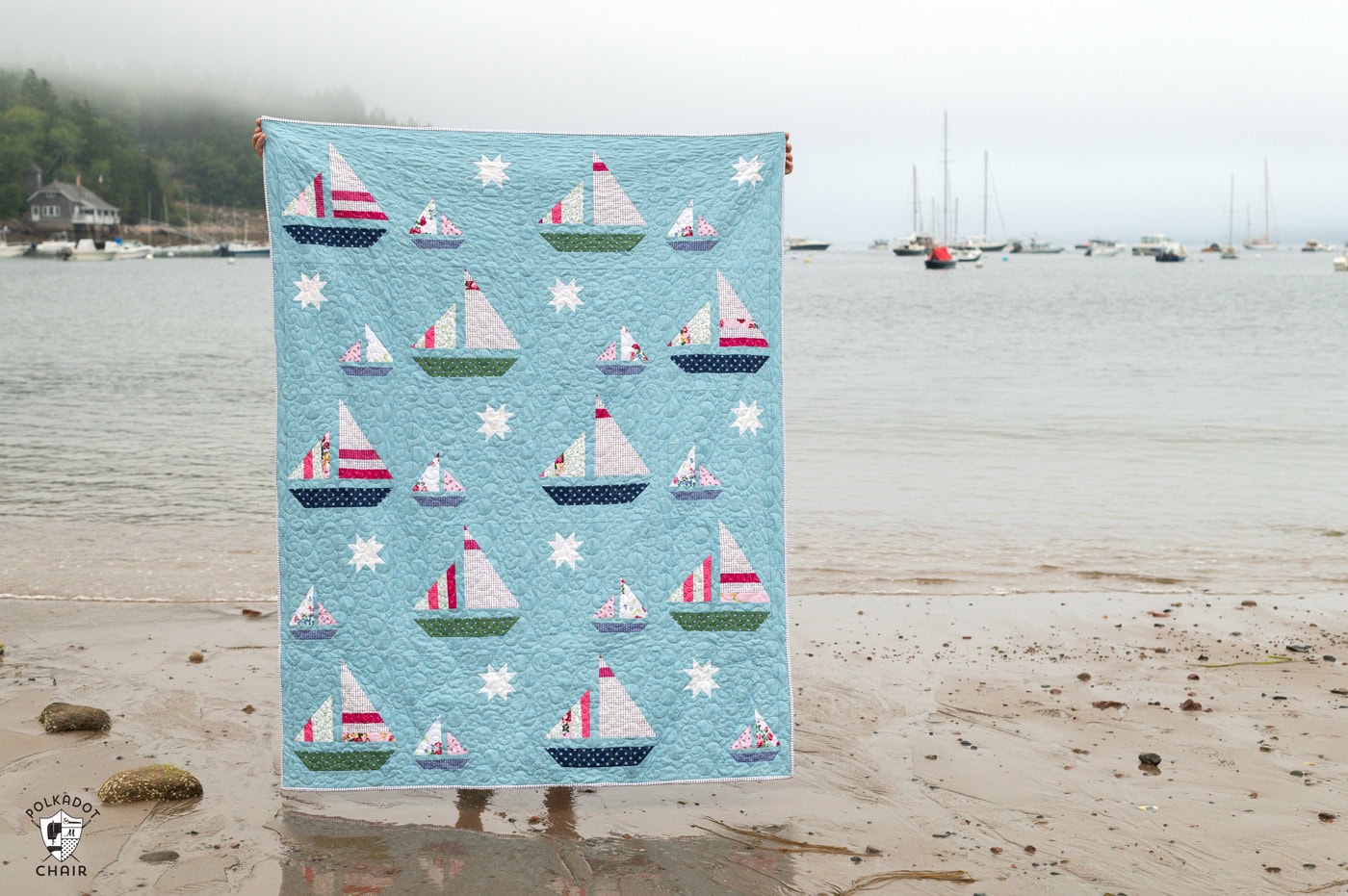 Blue quilt with white, red and green sailboat quilt blocks outdoors