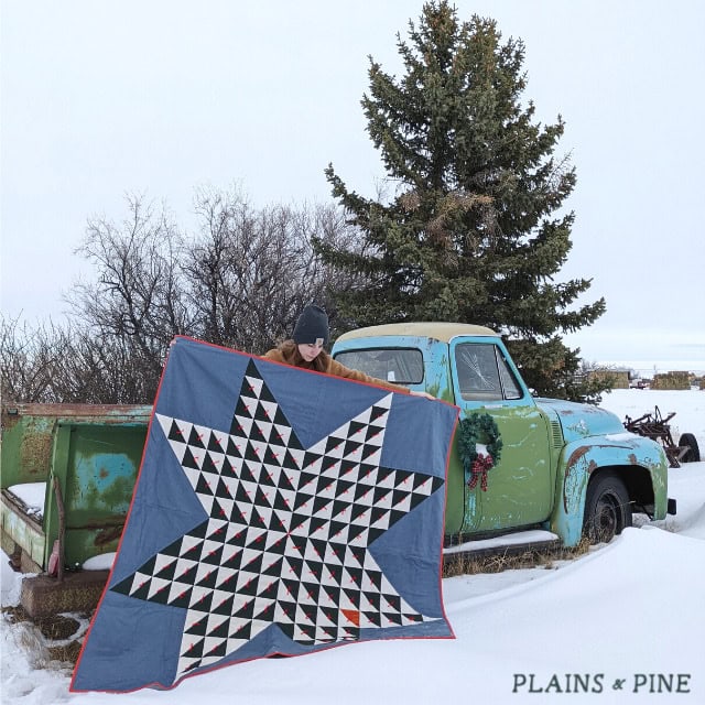 colorful star quilt outdoors with old truck and snow