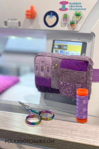 purple pincushion attached to white sewing machine with sewing notions