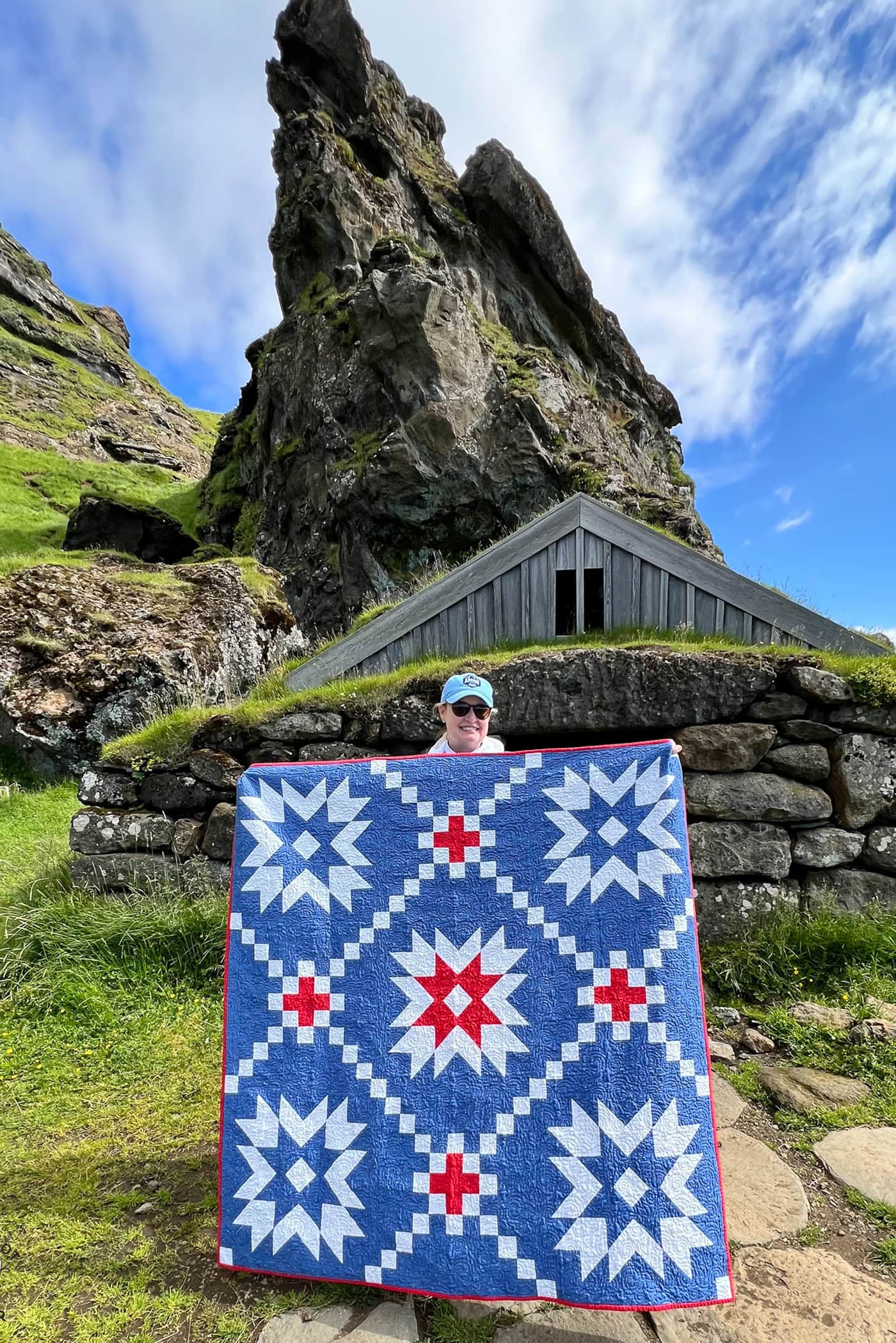 woman holding blue and red quilt in front of mountain