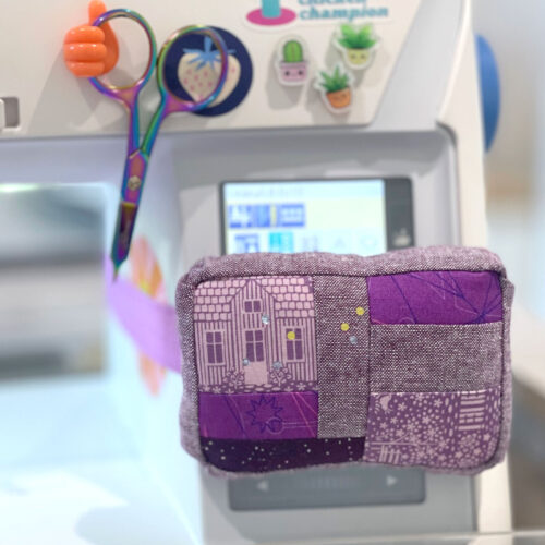 purple pincushion attached to white sewing machine with sewing notions