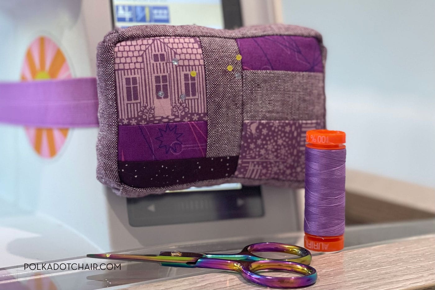 purple pincushion attached to white sewing machine with sewing notions