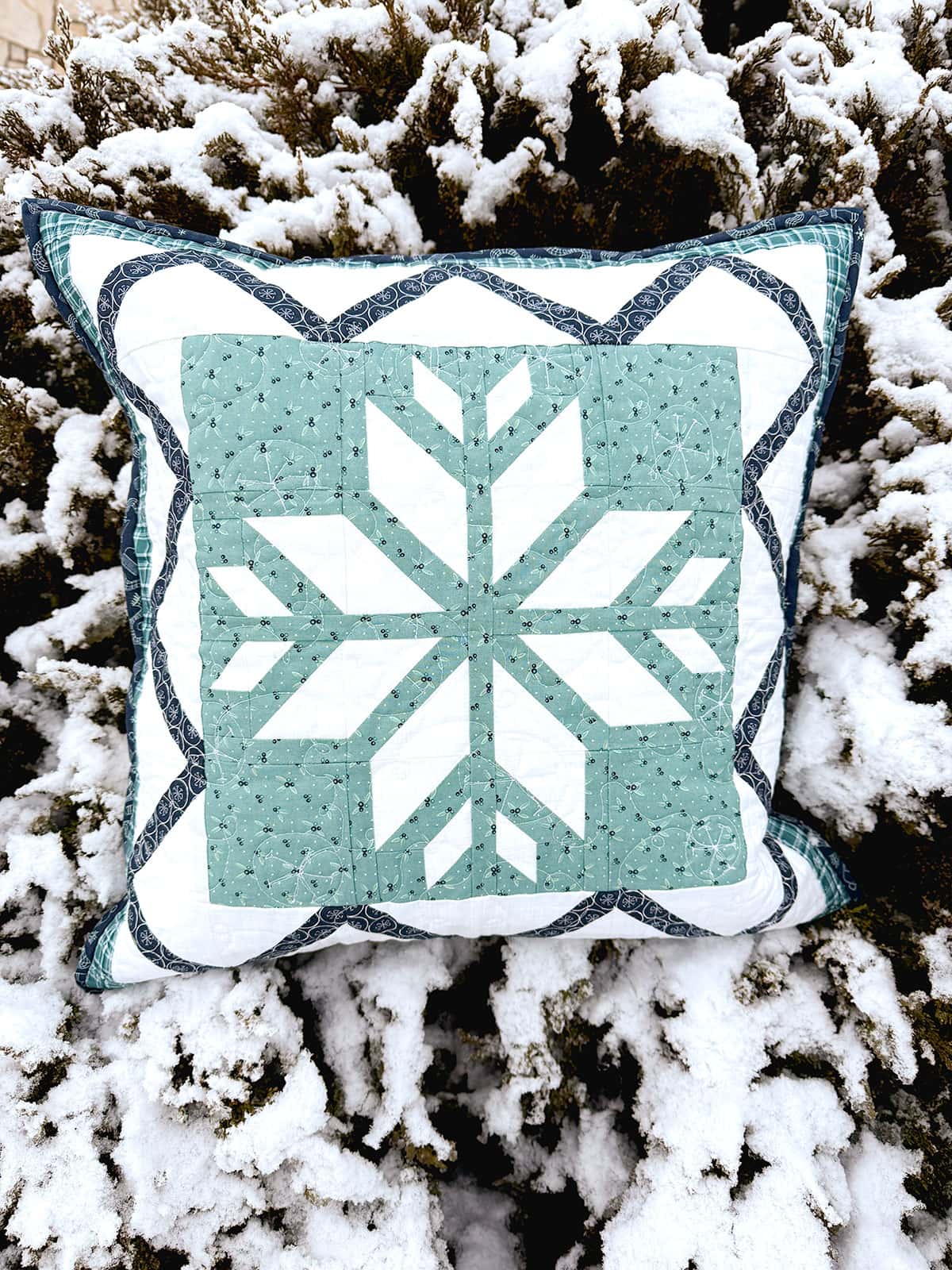 Aqua and white quilted pillow outdoors in the snow