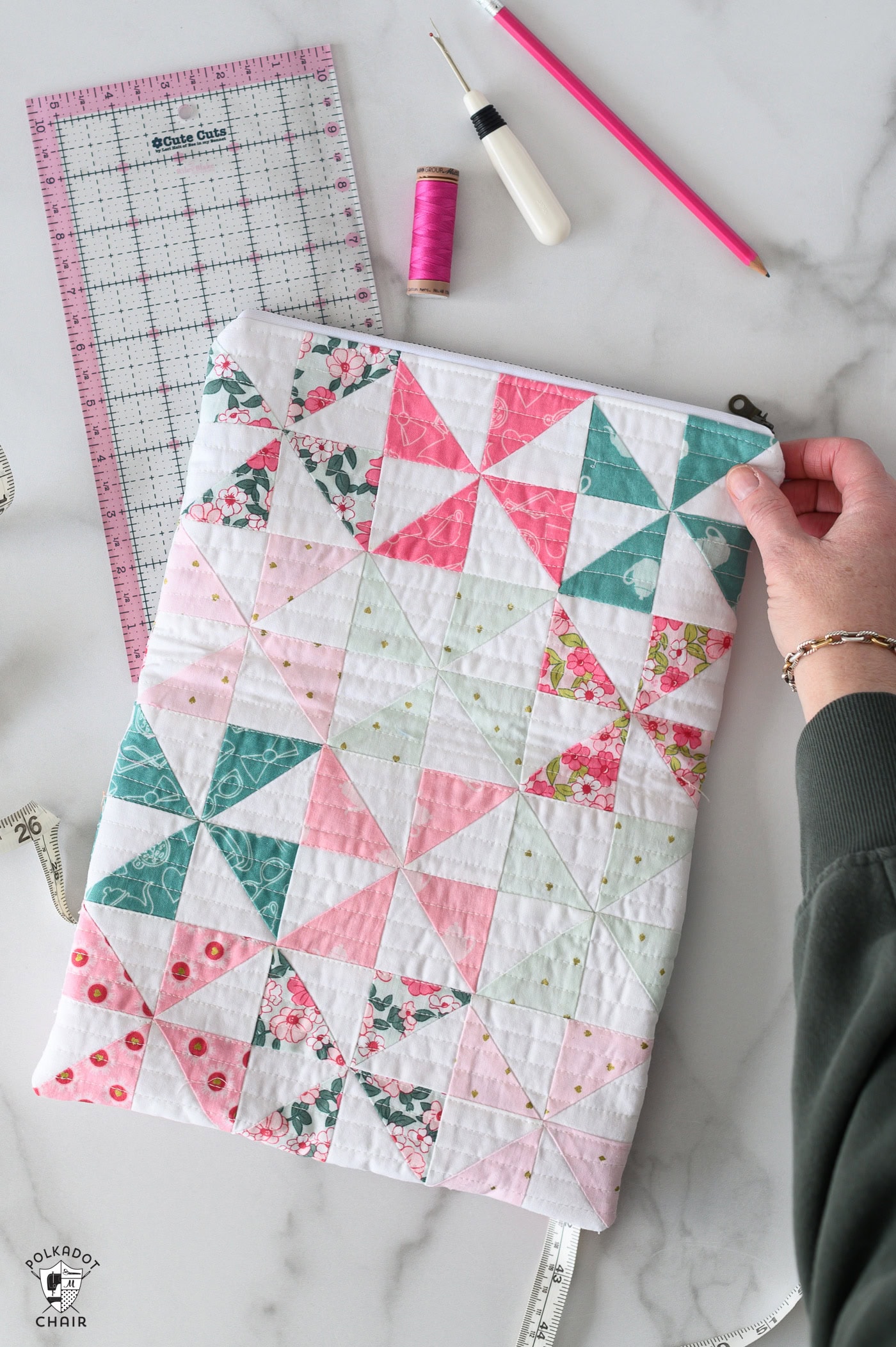 Pink aqua and blue quilted zip pouch with sewing accessories on white table