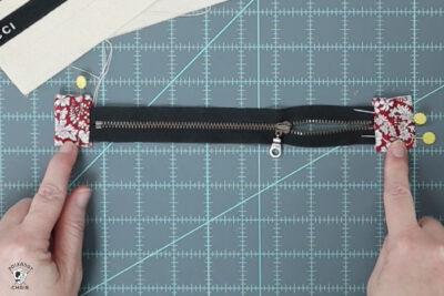 hand pointing at fabric on ends of zipper