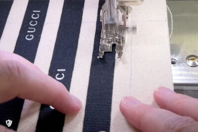sewing machine sewing black ribbon to canvas