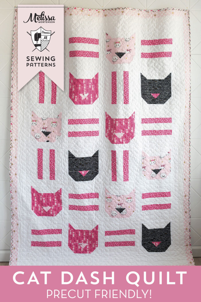 black white and pink cat quilt hanging on wall