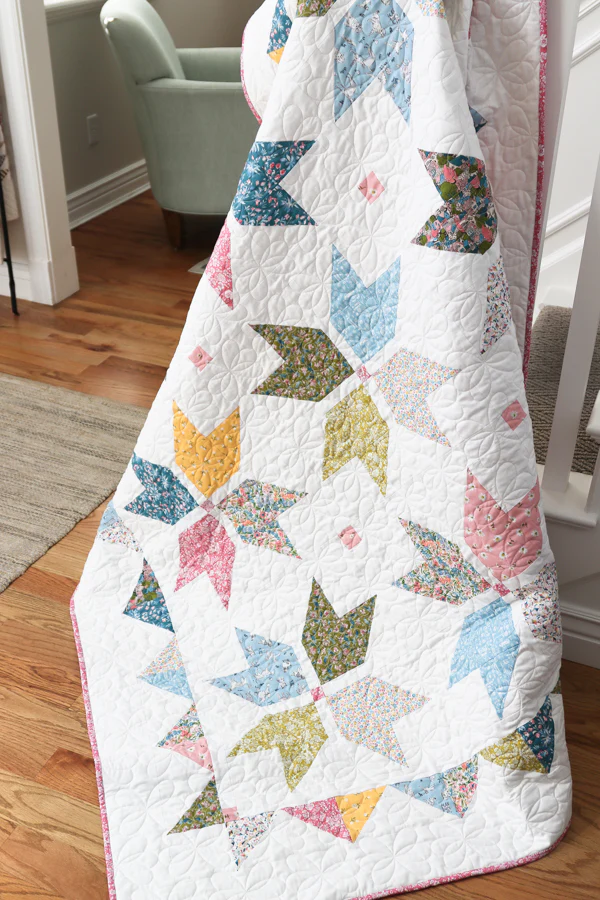 geometric quilt with pink, blue and soft spring colors draped in house