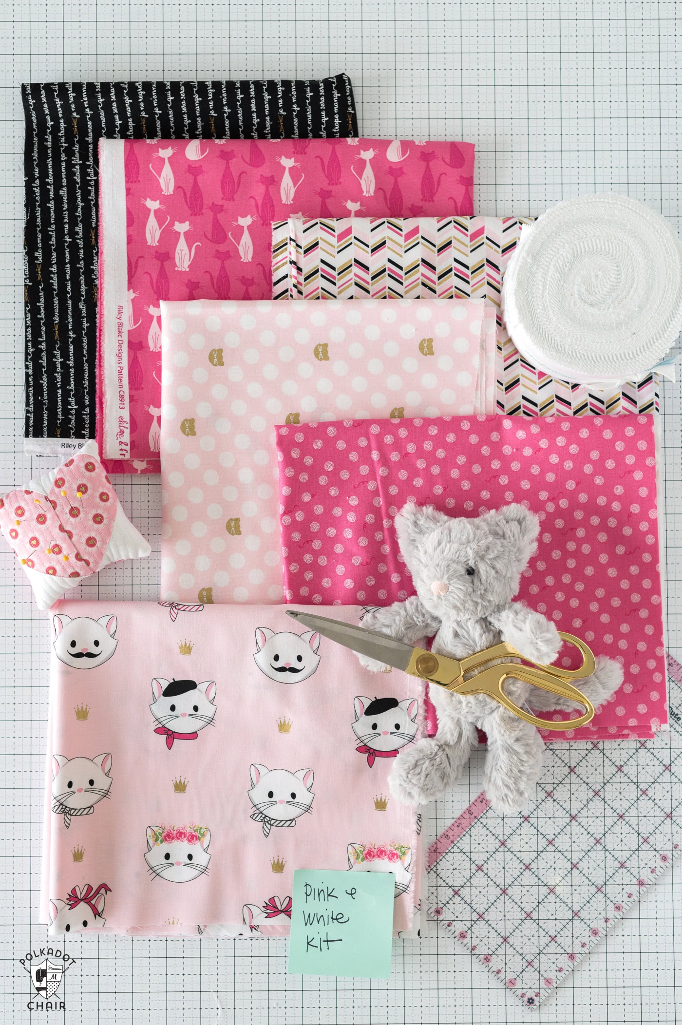 pink fabric with sewing notions on white cutting mat