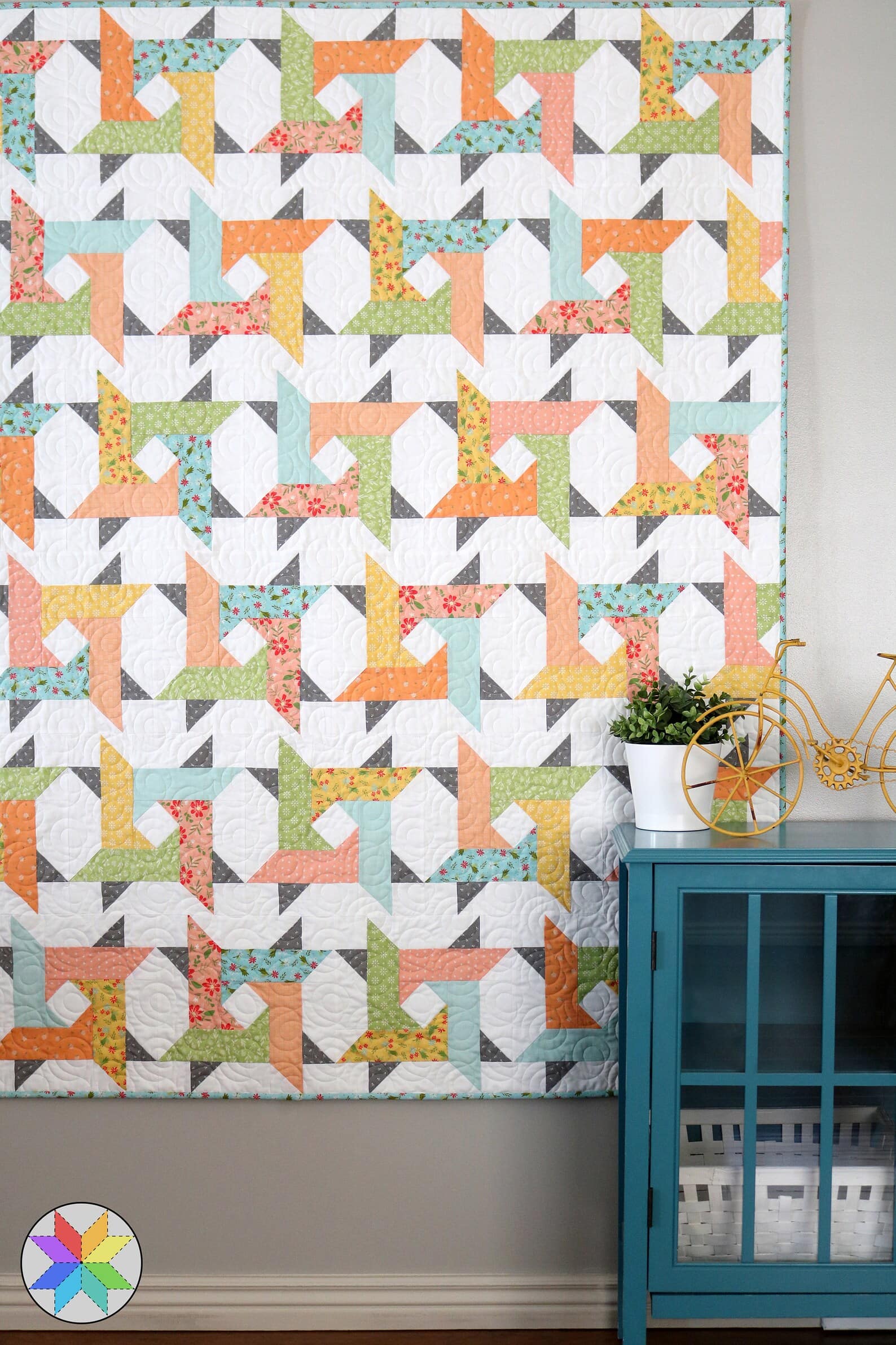 geometric quilt in bright colors hanging on wall in home